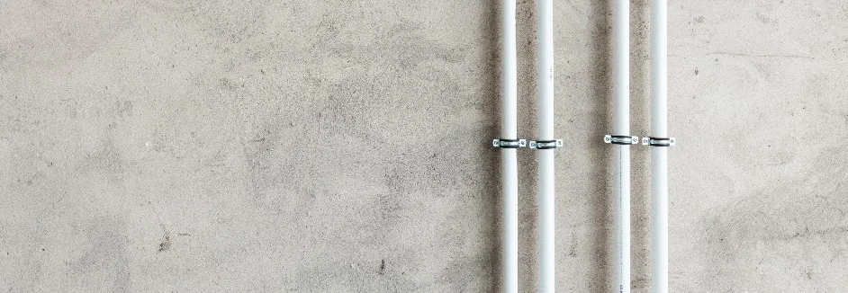 Vier weiße Rohre an Betonwand